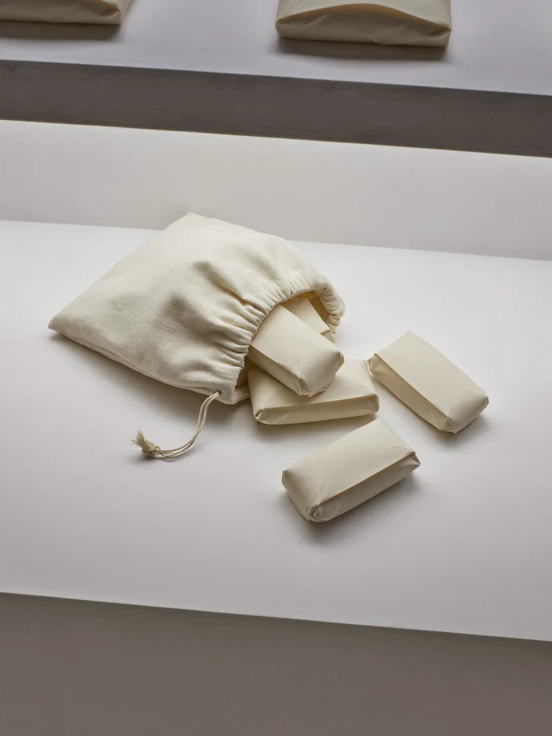 Illustration eines Leinenbeutels mit kleinen verpackten Mitbringseln auf weißem Tisch